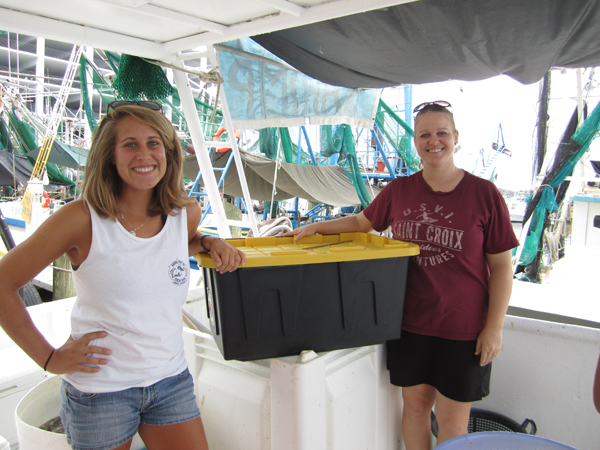 Olivia Carelli and Jennifer Hill of Dauphin Island Sea Lab deliver a transport box to the Capt. Justin, a shrimping vessel in Biloxi.